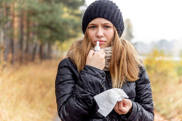 young woman with runny nose and using a nasal spray - Fotó, kép