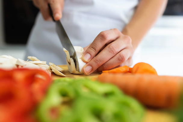 Close-up of hands of healthy young woman cutting fresh vegetables in the kitchen at home. - Photo, image