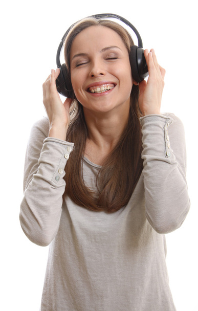 Νεαρή γυναίκα ακούει μουσική με ακουστικά - Φωτογραφία, εικόνα