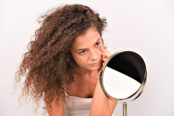 孤立した白い背景に鏡を通して見る巻き毛の若いアフロ女性 - 写真・画像