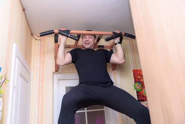 Family daily in focus: Handsome strong man doing pull-ups at home - Fotó, kép