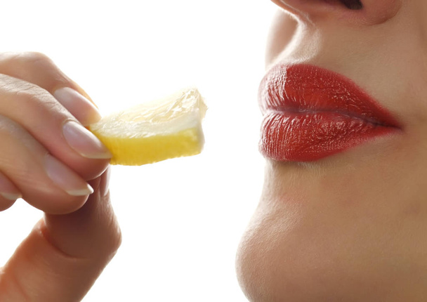 beautiful woman licks and eating piece of orange on a white background. Great food for a healthy lifestyle. - 写真・画像