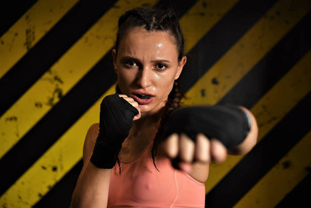 young woman with boxing gloves on a dark background - Photo, Image