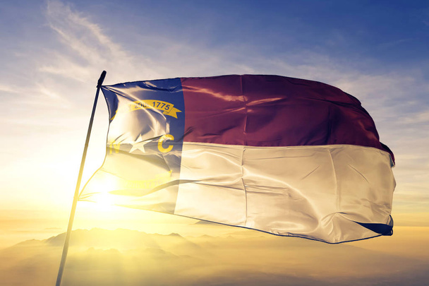 Штат Северная Каролина Флаг США текстильная ткань ткани размахивая на вершине тумана восхода солнца
 - Фото, изображение