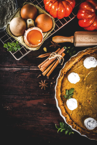 Autumn baking background, baking ingredients for pies, cookies - pumpkins, pumpkin pie, spices, flour, eggs, rolling pin, whisk, old wooden table top view copy space, with notebook for recipes - Photo, image