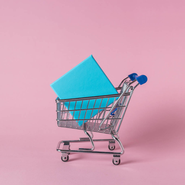 Gift boxes in shopping cart on pink background. Minimal sale concept. - Foto, Imagem
