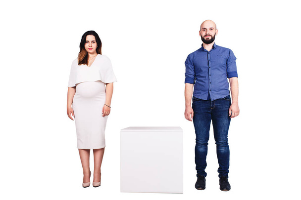 Una ragazza incinta e un ragazzo barbuto stanno in piedi e guardati. Isolato su bianco
. - Foto, immagini
