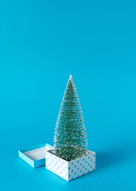 Creative layout of gift boxes and Christmas tree on blue background. Minimal Christmas or New Year concept. - Фото, изображение