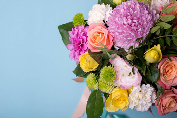 beautiful floral arrangement, pink and yellow rose, pink eustoma, green and pink chrysanthemum, white carnation, pink dahlia on a blue, turquoise background with space for text - 写真・画像