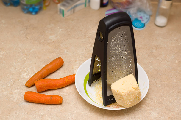 queso que se añadirá a una ensalada rallada en un rallador grande
 - Foto, imagen