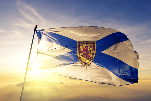 Новая Шотландия провинция Канады флаг текстильной ткани ткани размахивая на верхней части тумана восхода солнца туман
 - Фото, изображение