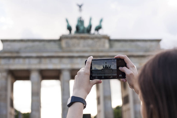 Hands holding phone mobile and takes pictures of Brandenburg Gat - 写真・画像