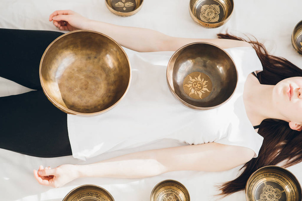 Young beautiful girl doing massage therapy singing bowls in the Spa. The concept of relaxation and alternative medicine. Toning. - Foto, Bild