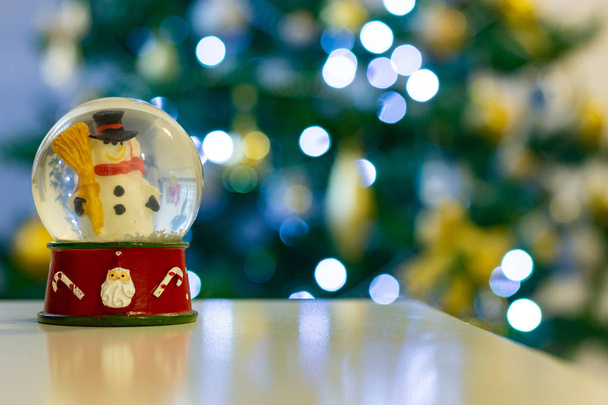雪だるまの雪の世界。雪だるまスノードーム クリスマス装飾クリスマス ツリーに defocussed ライトの前で. - 写真・画像
