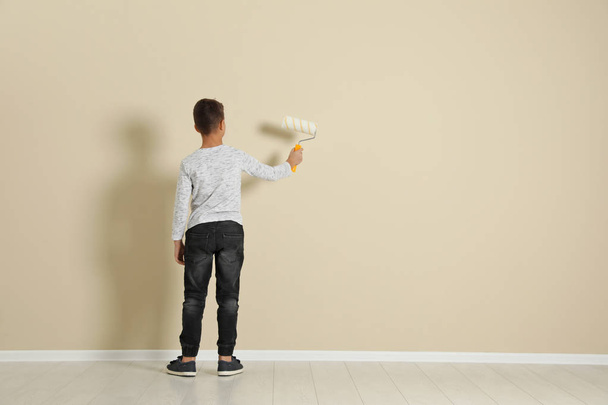 Child painting color wall with roller brush. Space for text - Photo, Image