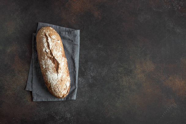Rye bread. Fresh homemade bread on dark rustic wooden background, top view, copy space. Sourdough artisan rye bread. - Photo, Image