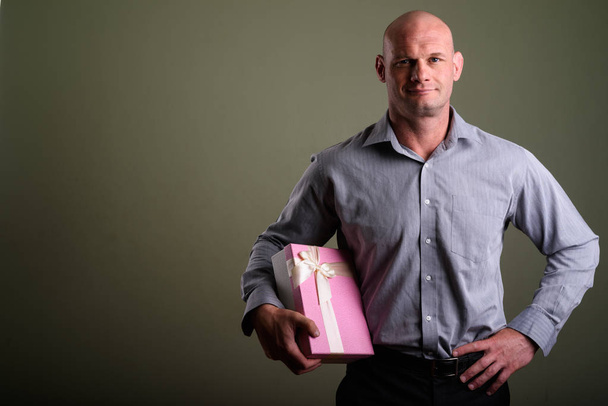 Portrait of bald muscular businessman against colored background - Zdjęcie, obraz