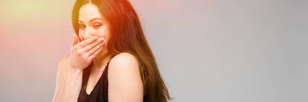 Portrait of emotional pretty confident plus size model standing in studio giggling on gray background - Photo, Image