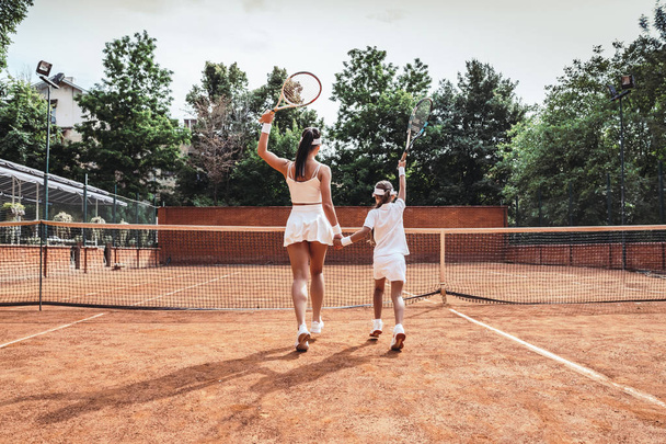 Girl with her mother play tennis on the tennis court, view from the back. - Fotografie, Obrázek