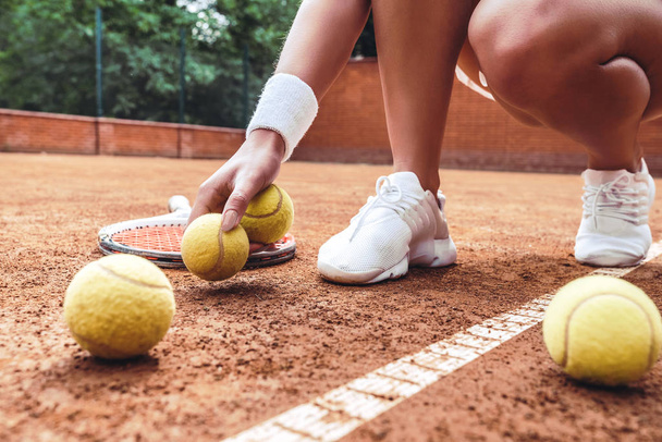 Tennis is her life. Cropped closeup of sporty female legs on tennis court. Beautiful woman tennis player picks up tennis ball off the ground. Sports Fashion. - Zdjęcie, obraz