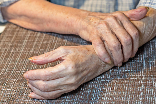 The hands of an elderly woman with Parkinson's disease tremble. Trembling hands of an elderly woman. - Photo, Image