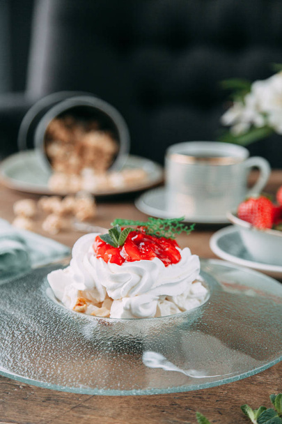 Pavlova dessert with berries in a beautiful composition. Foodstyling on a wooden background with coffee and strawberries. - Foto, immagini