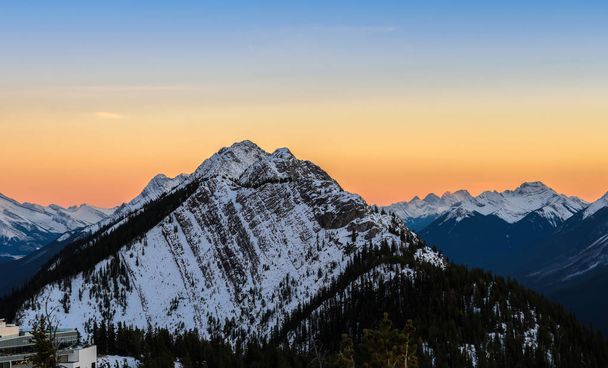 Потрясающий закатный горизонт снега покрыл Канадские Скалистые горы в Национальном парке Банф в Альберте, Канада. Вид с Банфской Гондолы
. - Фото, изображение