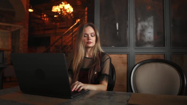 Eine junge Frau sitzt in einem Café am Holztisch, trinkt Kaffee und benutzt ihr Smartphone. Mädchen surfen im Internet, chatten, bloggen. Frau hält Telefon in der Hand und schaut auf seinen Bildschirm. - Filmmaterial, Video