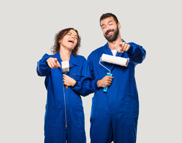 Painters pointing with finger at someone and laughing a lot on isolated grey background - Fotoğraf, Görsel