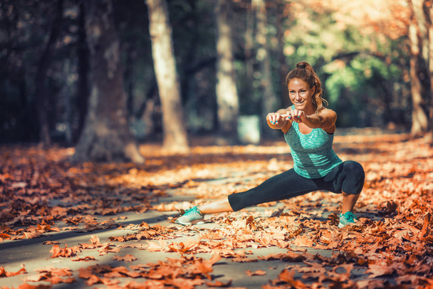 Žena, táhnoucí se v parku, na podzim. - Fotografie, Obrázek