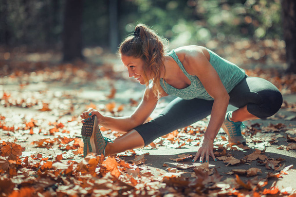 Woman stretching in the park, in the fall. - Photo, Image