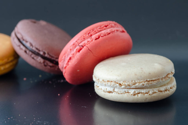 Colorfull macaroons on dark background.Pink, cream, and brown color macaroons.top view
. - Фото, изображение
