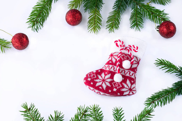 Calcetín rojo de Navidad y bolas de decoración sobre fondo blanco, marco de ramas de árbol contiferas verdes - Foto, Imagen