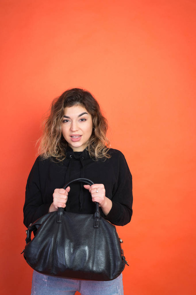 Shopping abstract: beautiful girl with a black bag over orange color background - Foto, imagen