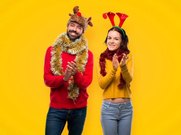 Couple habillé pour les vacances de Noël applaudissements après présentation dans une conférence sur fond jaune
 - Photo, image