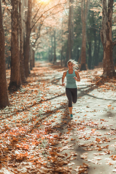 Γυναίκα τρέξιμο σε εξωτερικούς χώρους το φθινόπωρο σε δημόσιο πάρκο - Φωτογραφία, εικόνα