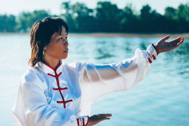 Ázsiai nő a hagyományos ruhát gyakorolják a Tai Chi, a tó partján - Fotó, kép