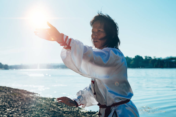 湖のほとりに太極拳の練習従来の衣類でアジアの女性 - 写真・画像