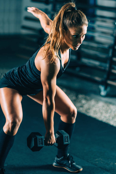 Cross training. Young woman exercising with dumbbell - Foto, imagen
