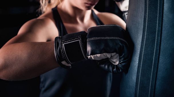Imagen de cerca de una mujer rubia fuerte golpeando la bolsa de boxeo
. - Foto, Imagen