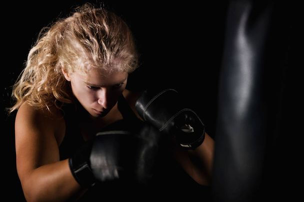 blonde woman hitting the black boxing bag - Zdjęcie, obraz