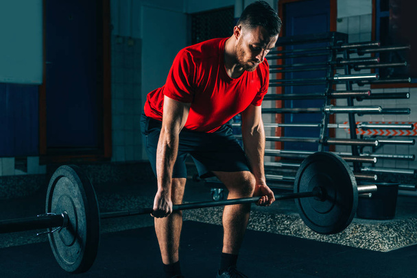 Cross training. Male athlete lifting heavy barbell weights  - Фото, зображення