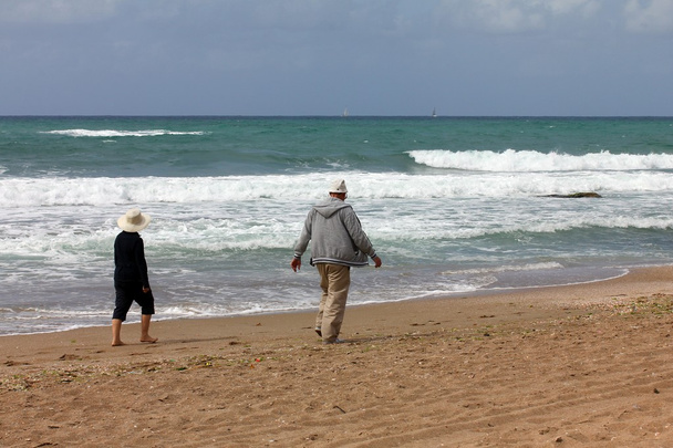 Старша пара ходить окремо на пляжі
 - Фото, зображення