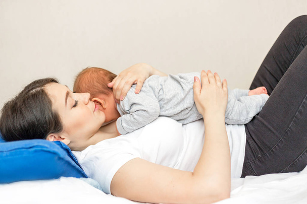 Young mother holding her newborn son. Mom nursing an infant - Photo, image