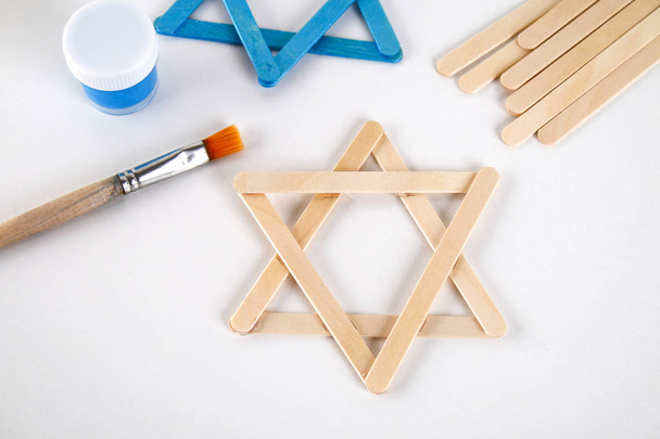 DIY. Hanukkah decor. Star of David from ice cream sticks on a white wooden table. Guide, step by step on the photo. Diy on Hanukkah - Foto, immagini