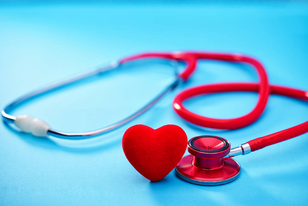 Red heart and stethoscope or phonendoscope on on blue background.Selective focus. - Fotó, kép