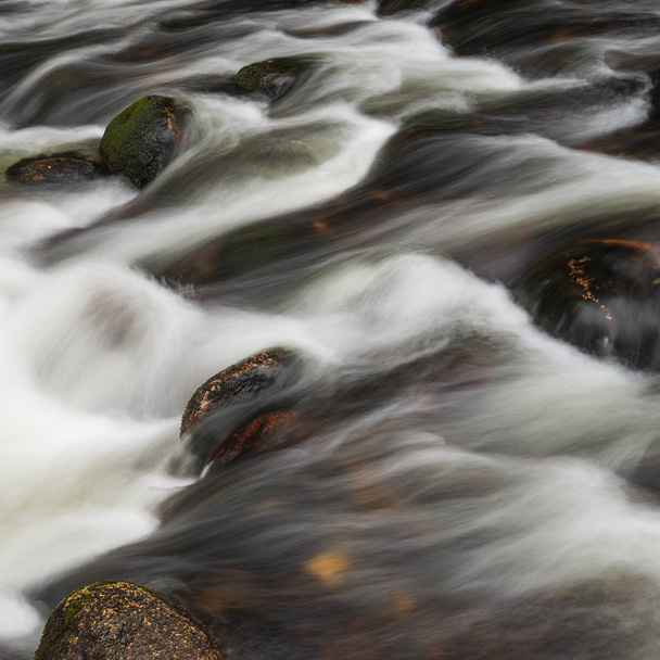 Detail landschap foto van rivier stroomt over rotsen met lange blootstelling motion blur - Foto, afbeelding