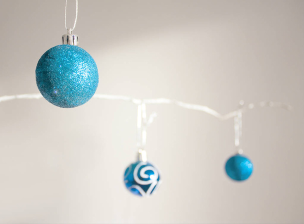Κομψή σύνθεση Χριστούγεννα με μπλε στολίδια στο λευκό κλάδο σχετικά με το λευκό φόντο - Φωτογραφία, εικόνα
