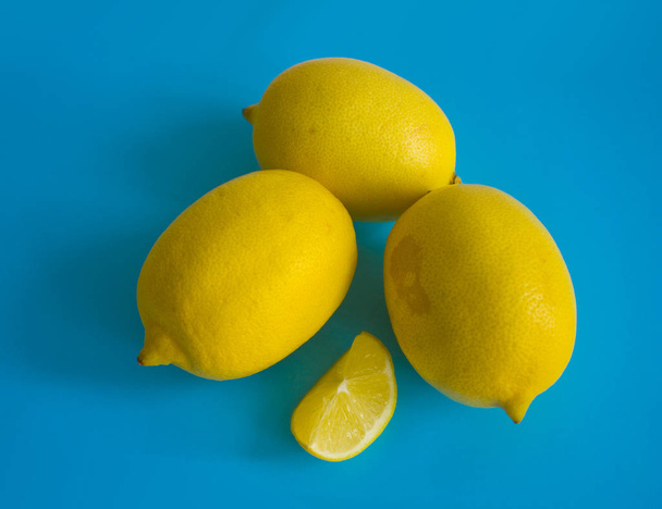 Ripe yellow lemons with slice isolated on the blue background - Foto, imagen