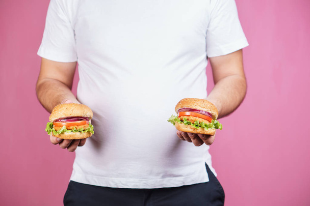 fat man with two burgers. hunger, unhealthy diet - Foto, Bild
